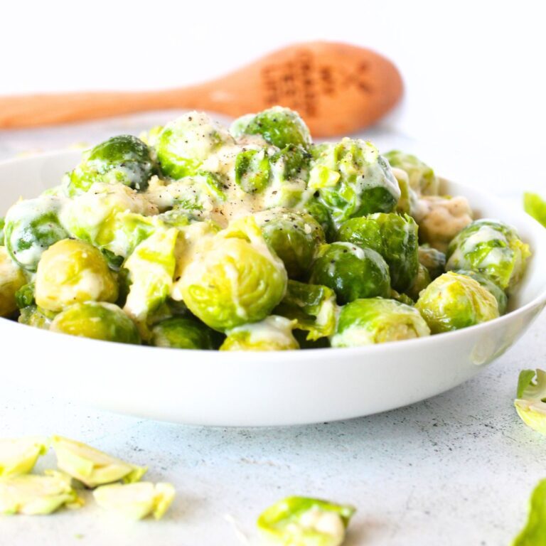 a bowl of creamy Brussels sprouts with a wooden spoon