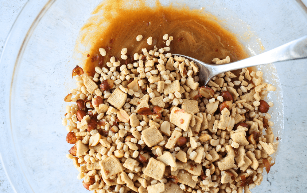 top view of a spoon mixing the keto cereal together with the high fiber syrup and peanut butter mixture before pressing into keto cereal bars
