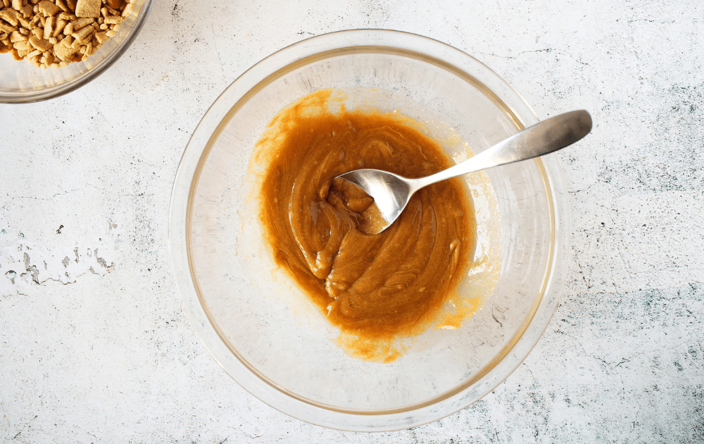 top view of mixing bowl with a spoon combining the sugar-free tapioca fiber syrup, peanut butter and keto sweetener.