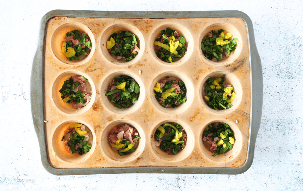 top view of copycat Starbucks egg white bites with the filling of spinach, ham and banana peppers in each muffin well before egg white is added