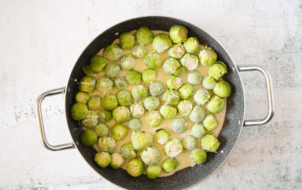 top view of a skillet filled with Brussels sprouts and cream before being braised