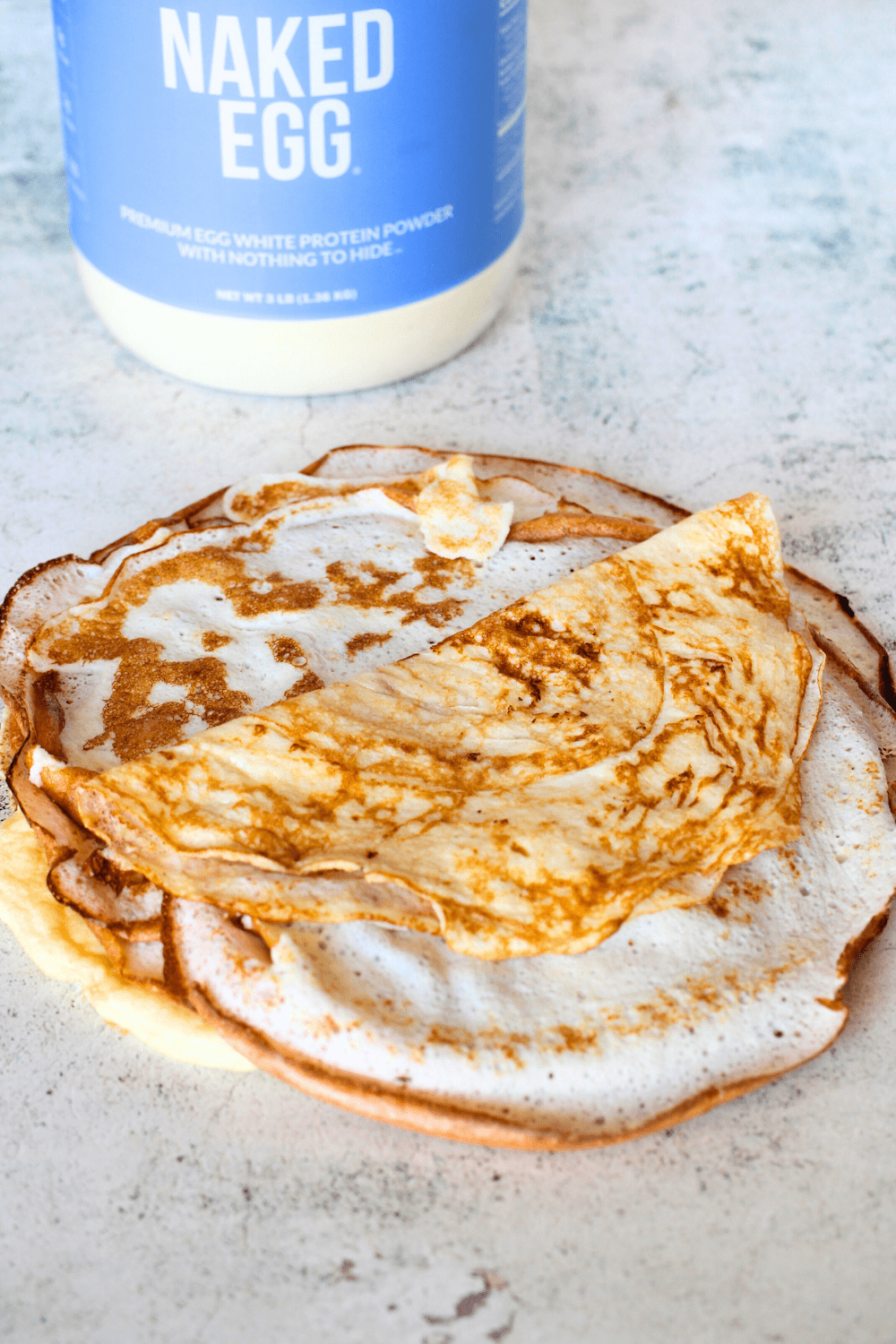 high protein keto recipe made with naked egg white protein powder in the background and the high protein crepes in the front