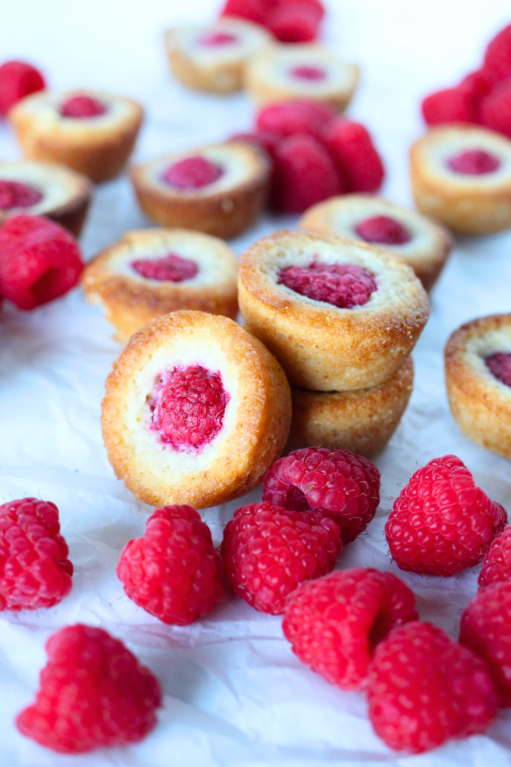 easy keto cookies with raspberries stacked on top of each other with fresh raspberries scattered around