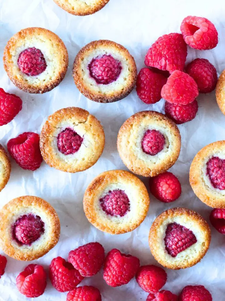 top view of keto raspberry financier cookies scattered around with fresh raspberries