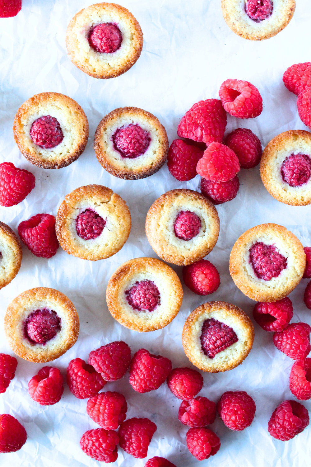 top view of keto raspberry financier cookies scattered around with fresh raspberries