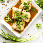 top view of high protein instant pot soy ginger fish with cilantro and green onions on a serving plate