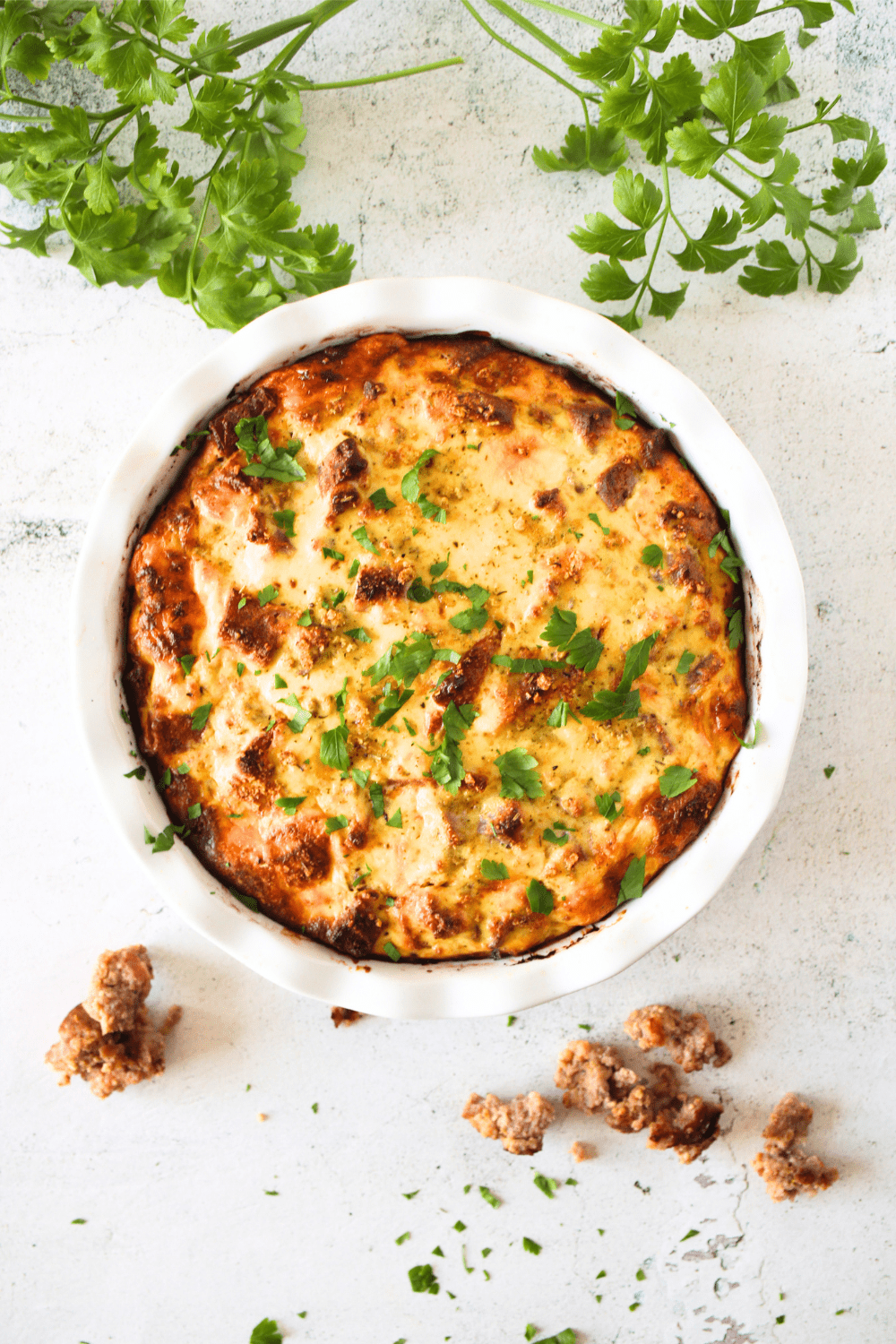 top view of a keto pizza rustica that is carnivore friendly with ground sausage, ricotta and fresh parsley scattered