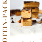 a copycat keto Snickers protein bar cut in half to show layers of protein nougar, peanuts, caramel and sugar-free chocolate