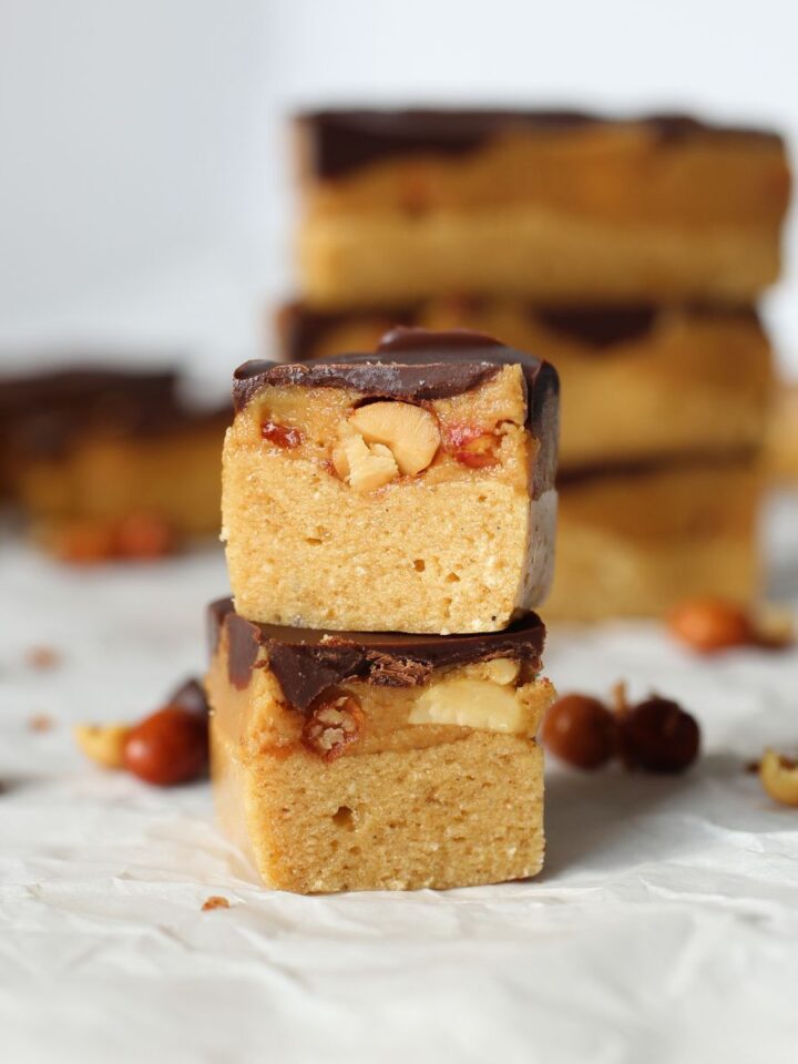 a copycat keto Snickers protein bar cut in half to show layers of protein nougar, peanuts, caramel and sugar-free chocolate