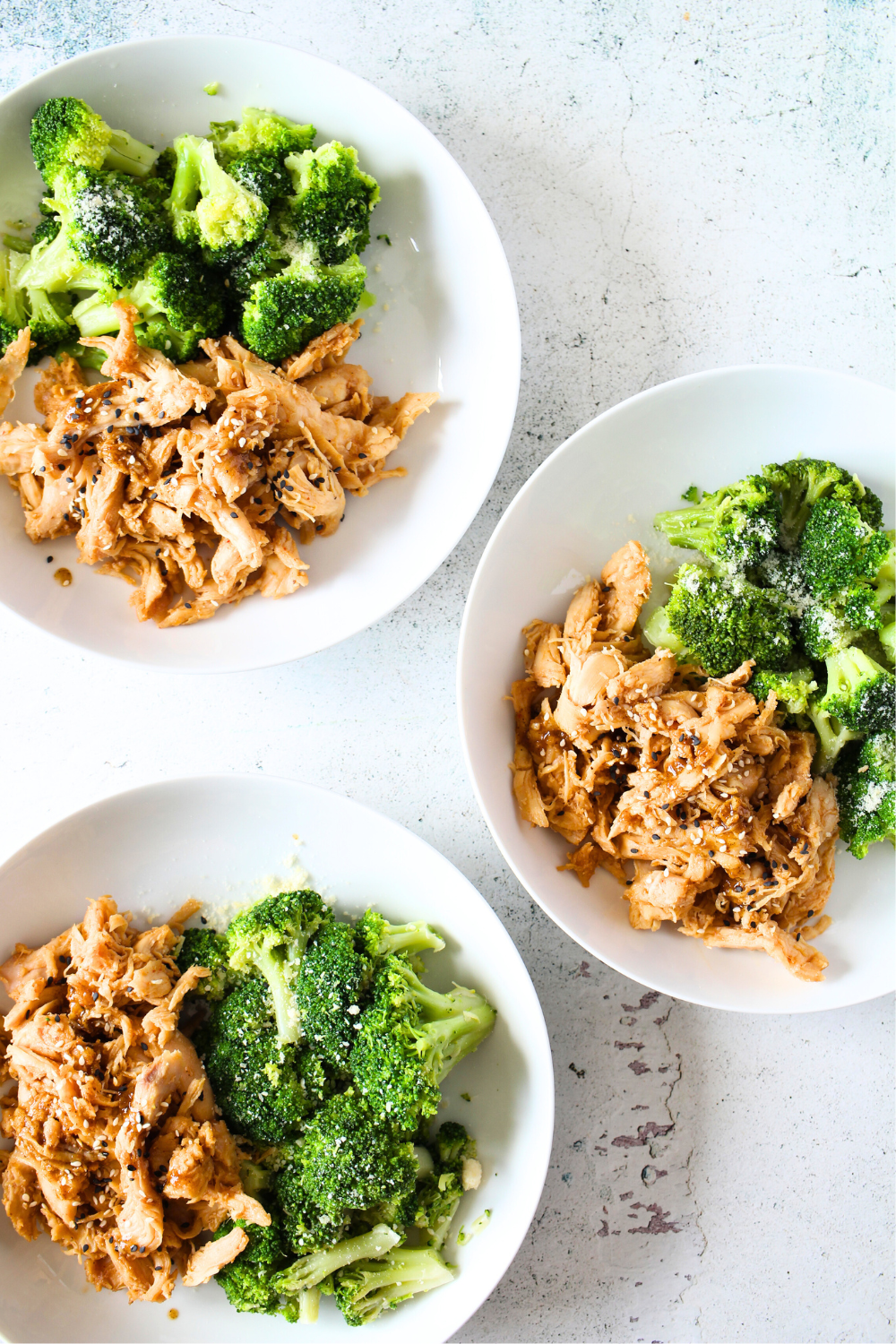 top view of 3 white bowls containing PSMF Sweet and Spicy slow cooker chicken with broccoli on the side.