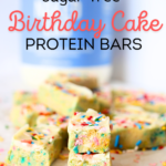 a PSMF Birthday Cake Protein bar cut in half with egg white protein powder in the background by Naked Nutrition