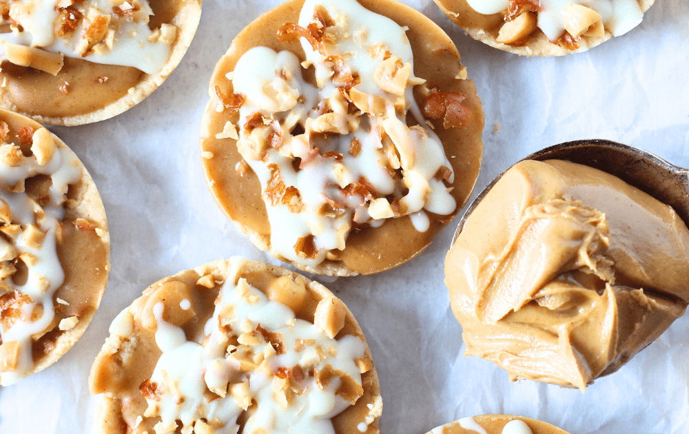 keto white chocolate peanut cups with a spoon of peanut butter