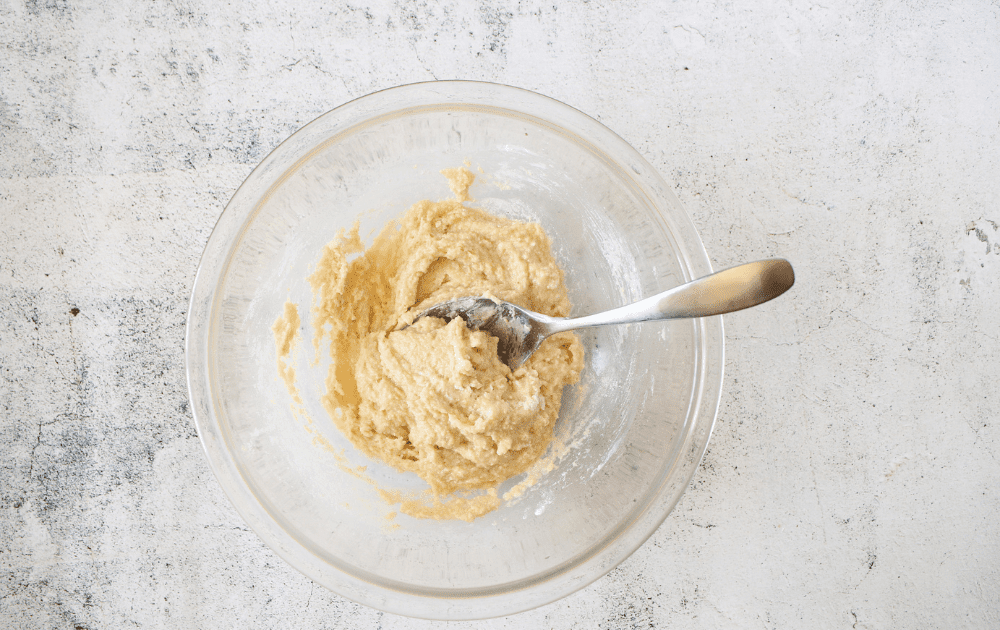 top view of a small mixing bowl with the dry ingredients for the keto strawberry cream roll cake along with the yogurt mixed together with a spoon.