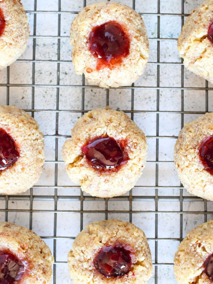 top vew of baked keto strawberry thumbprint cookies on a cooling rack