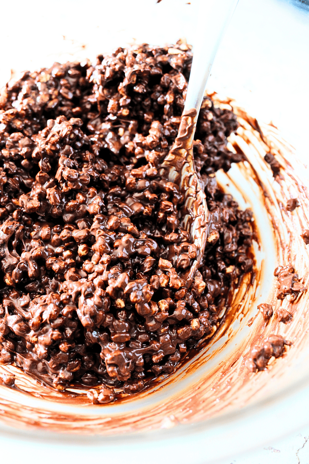 top view of copycat crunch bars with high protein cereal being mixed into the chocolate with a spoon