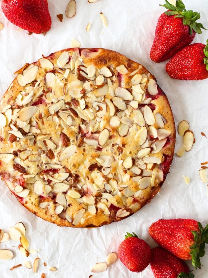top view of a Keto Strawberry Almond Frangipane cake topped with sliced almonds and fresh strawberries on the side