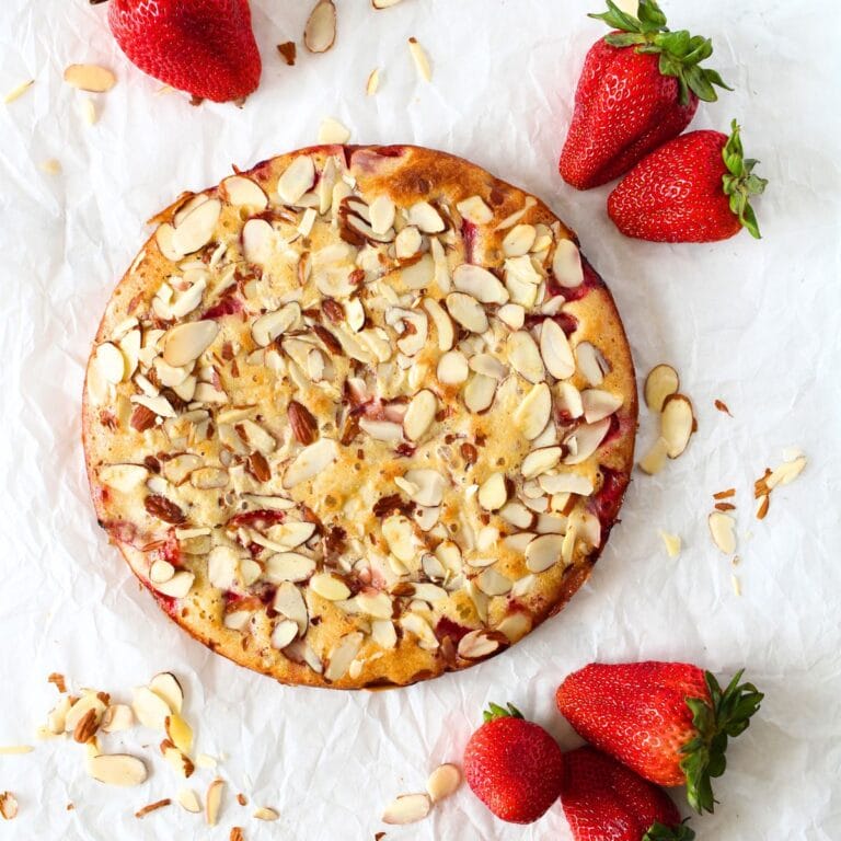 top view of a Keto Strawberry Almond Frangipane cake topped with sliced almonds and fresh strawberries on the side