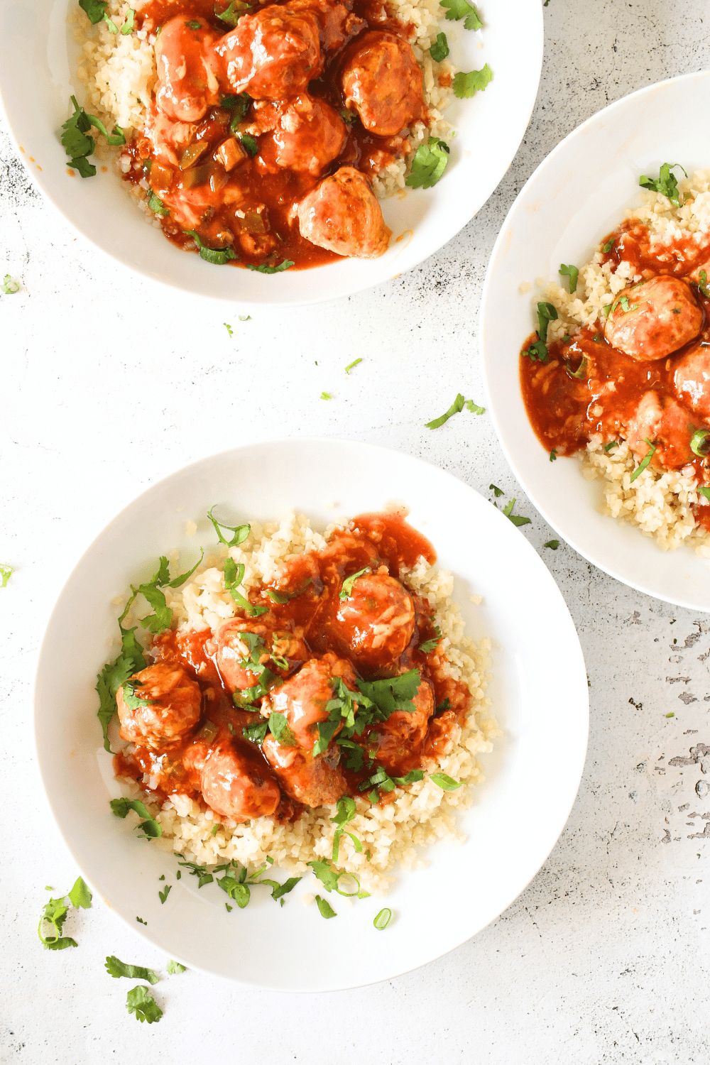 top view of bowls filled with riced cauliflower and easy PSMF enchilada meatballs