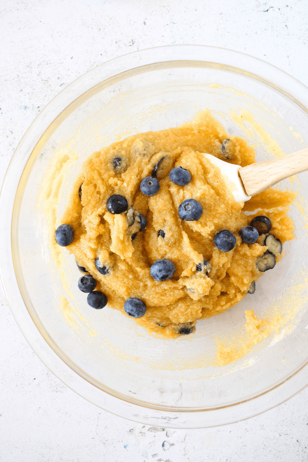 keto blueberry blondies batter with fresh blueberries being folded into the mixture with a spatula