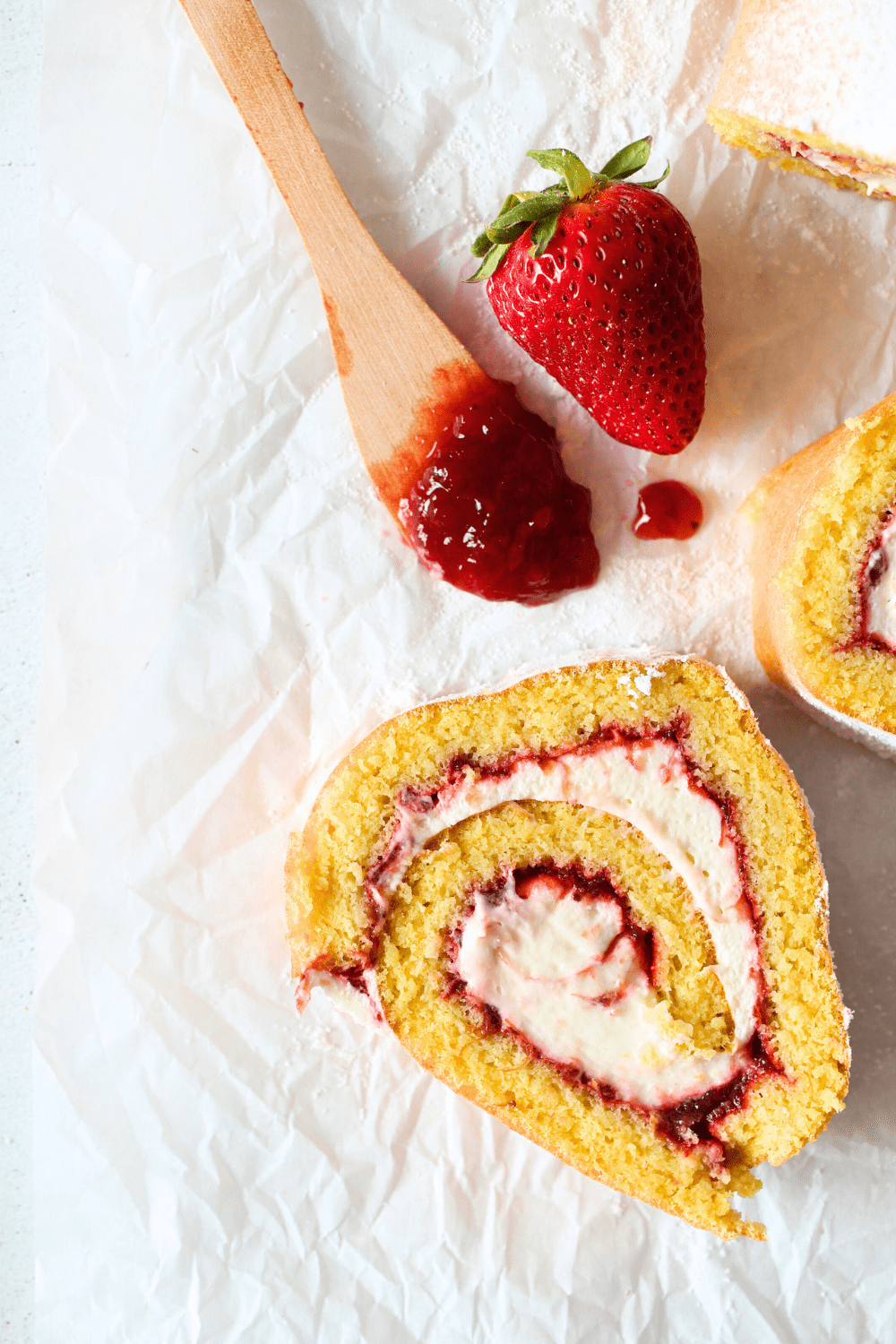 a slice of keto strawberry cream roll cake filled with a layer of sugar-free strawberry jam and strawberry whipped cream