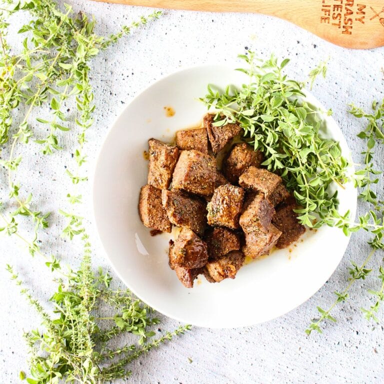 keto air fryer steak bites with fresh herbs and a wooden spoon