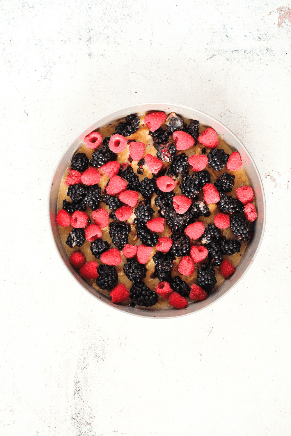 top view of the first layer of the keto upside-down cake made up of melted butter, sugar-free substitute and berries