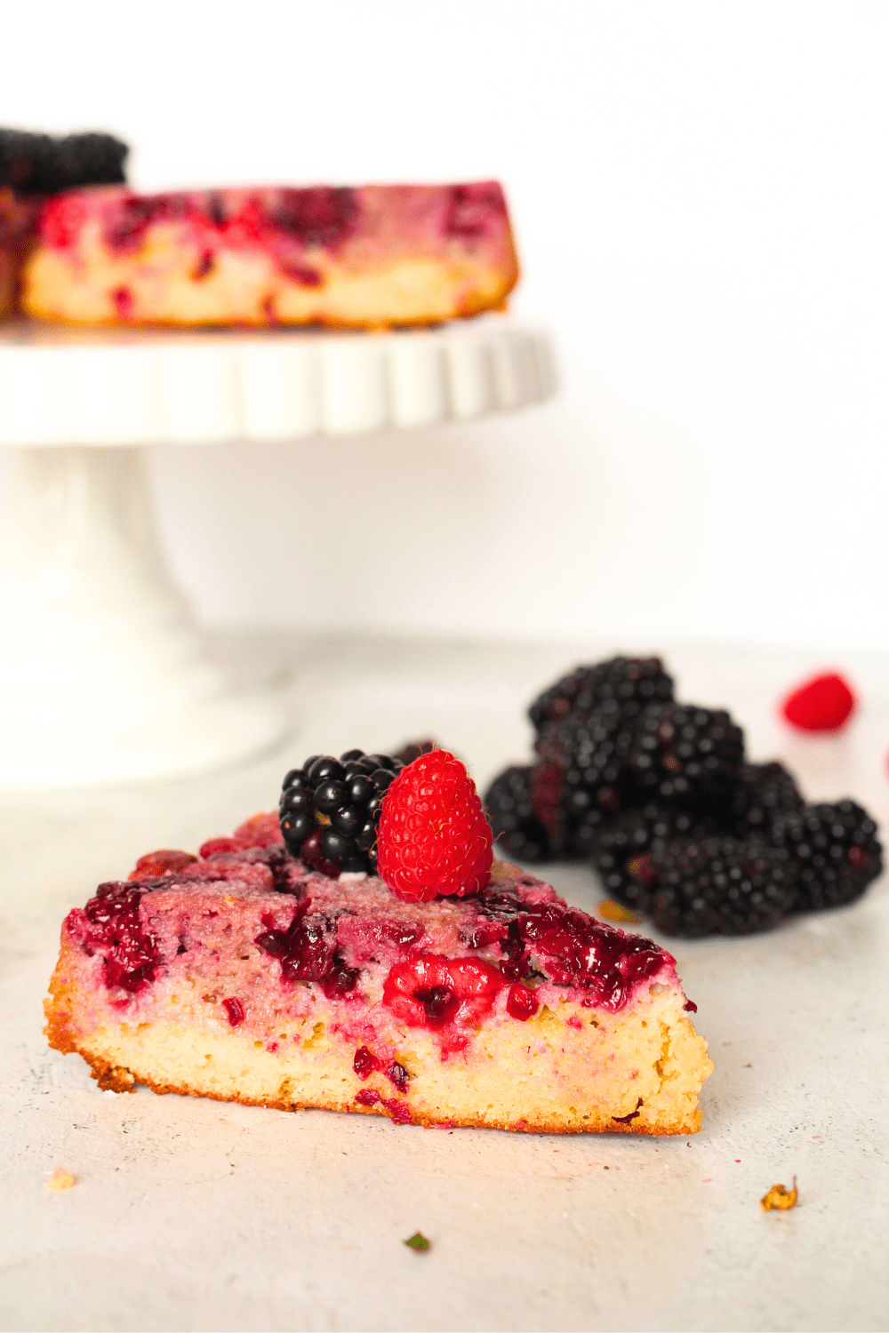 a slice of keto blackberry upside-down cake with fresh berries on top