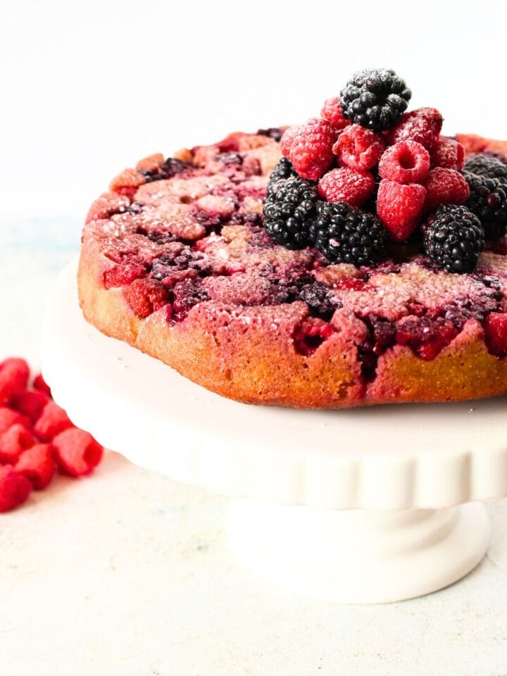 low carb blackberry cake on a cake stand with blackberries and rapsberries