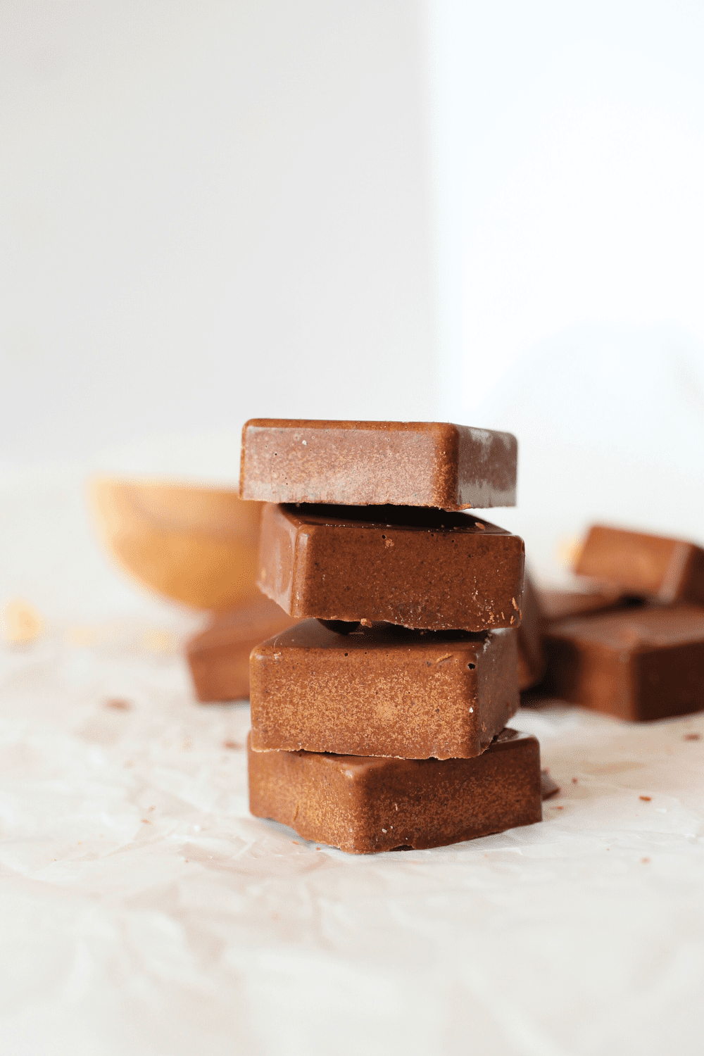 easy keto protein bar stacked on top of each other with cocoa butter scattered in the background