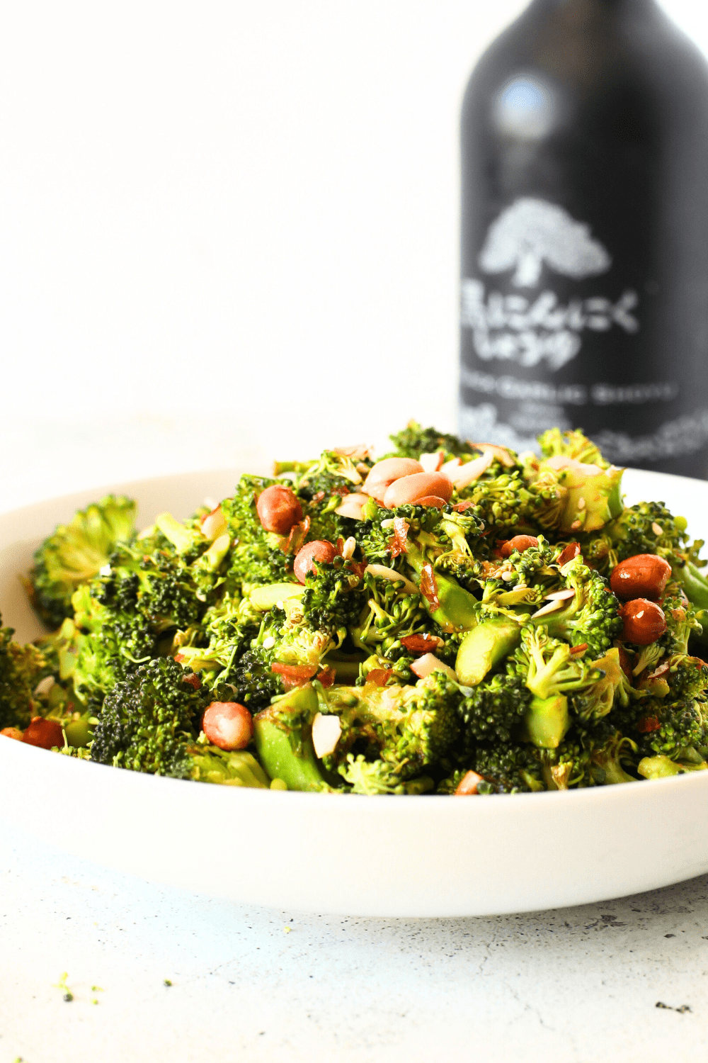 quick salad recipe using broccoli and soy sauce in a white bowl with soy sauce in the background