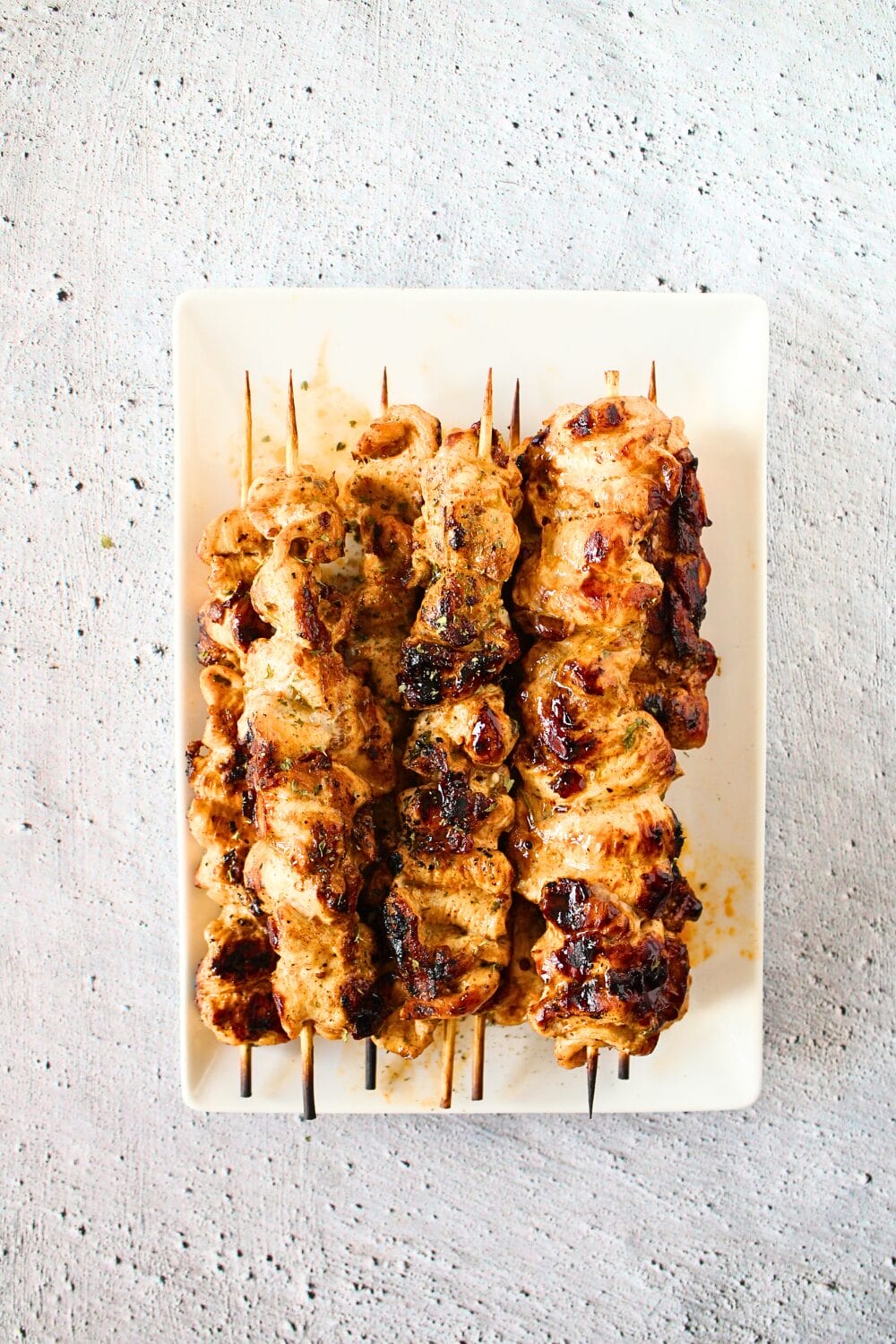 broiled keto chipotle chicken skewers on a white serving platter