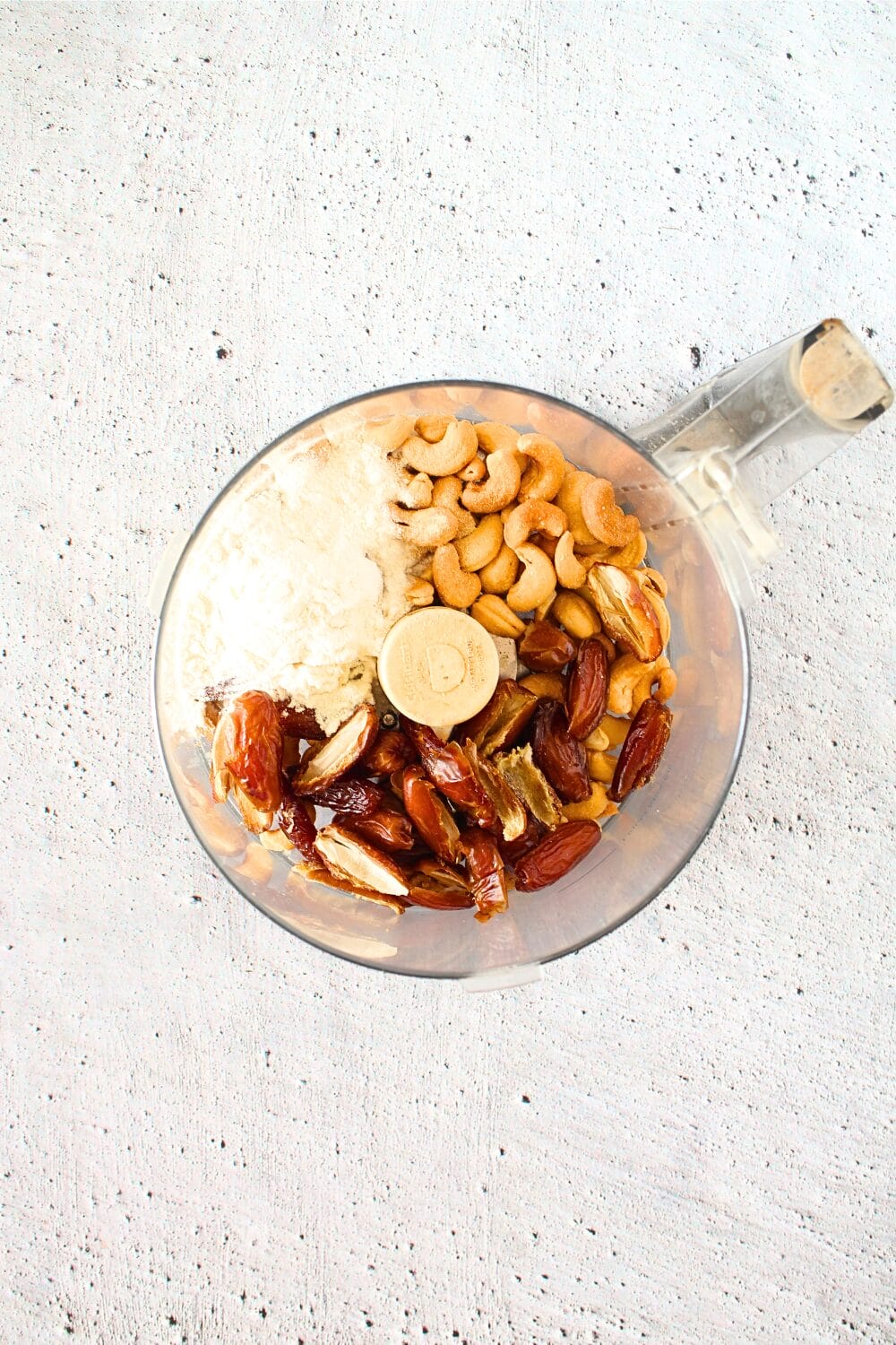 copycat protein larabar ingredients in a food processor including cashews, dates and protein powder