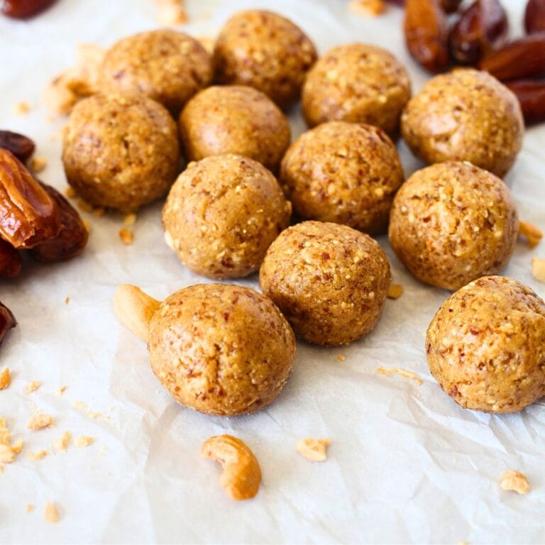 front view of healthy cashew cookie balls with dates and cashews scattered about
