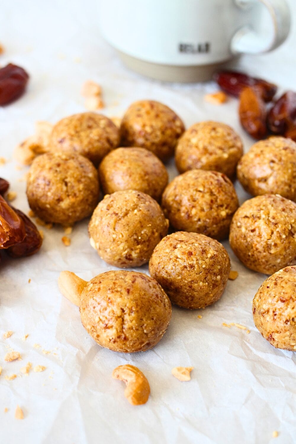 front view of healthy cashew protein bites made with dates, cashews and vanilla protein powder.  A cup of coffee is in the background