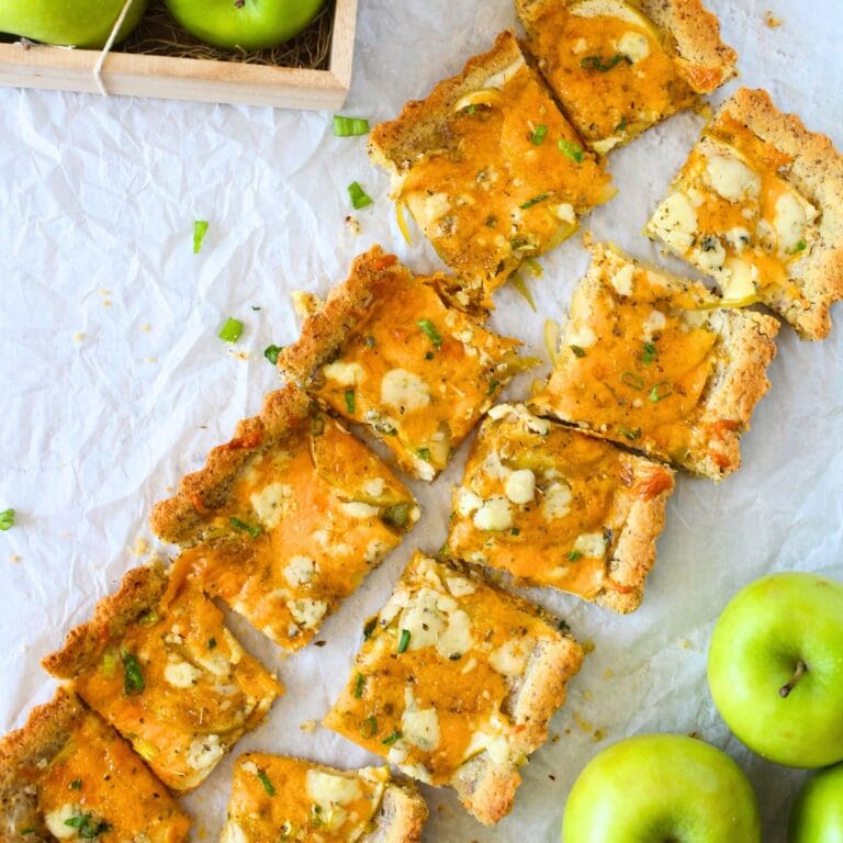 top view of keto cheddar apple tart divided into sections with fresh green apples in a basket.