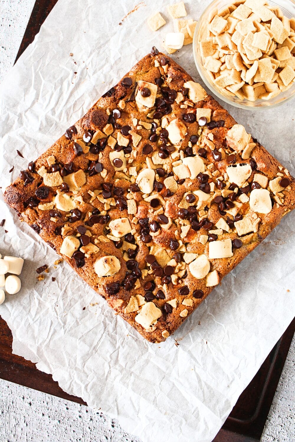 top view of keto s'mores bars after being baked. A bowl of keto graham cracker cereal and sugar-free marshmallows