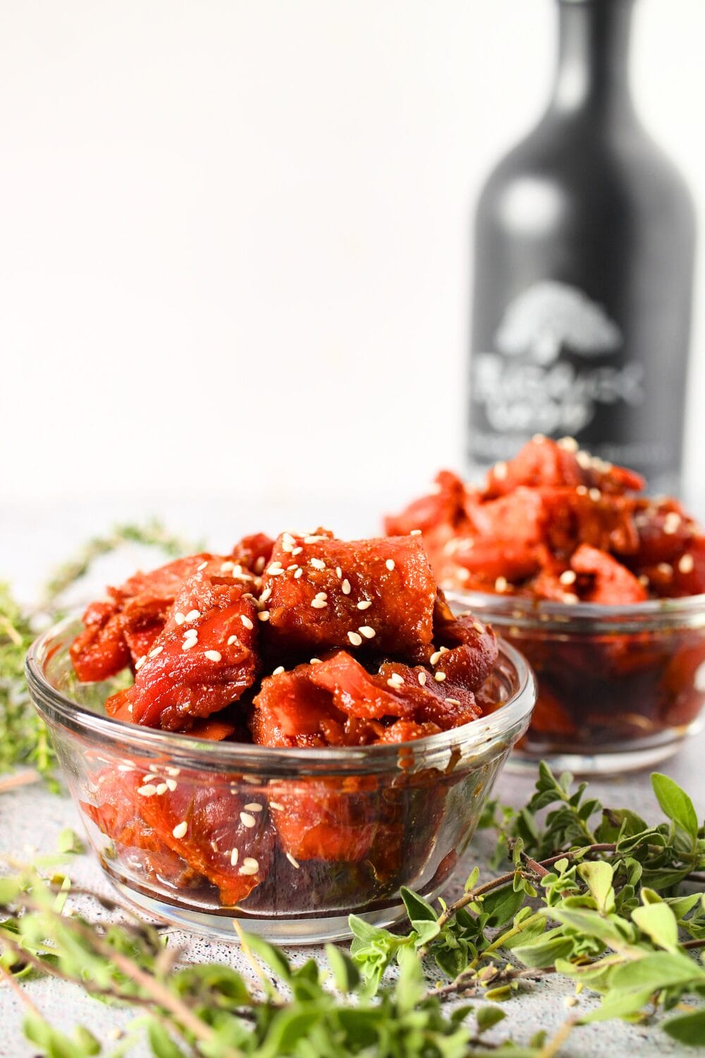 top view of keto salmon teriyaki poke in serving dishes with soy sauce and fresh herbs