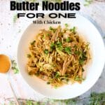 top view of a white bowl filled with keto warm almond butter noodles with chicken and sliced green onion with a spoon of almond butter to the side.