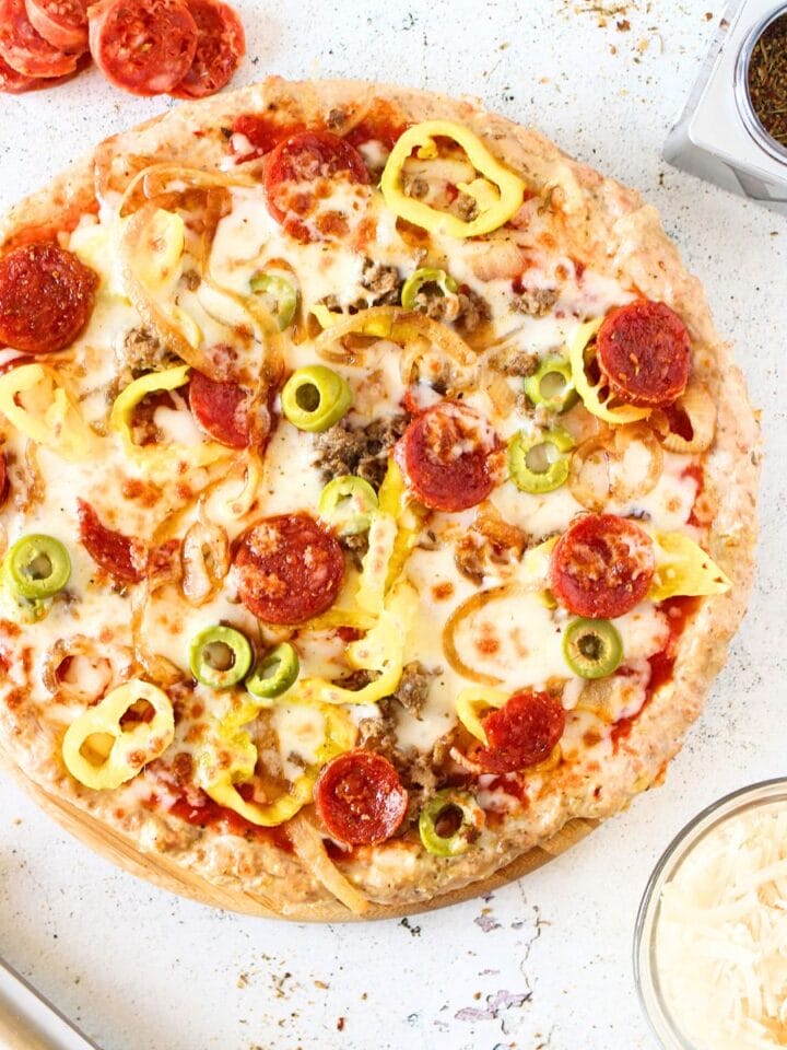 top view of a zero carb pizza crust recipe topped with high protein toppings and pepperoni and cheese on the side