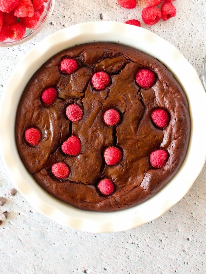 top view of easy keto chocolate molten lava cake with raspberries on top and scattered around the dish