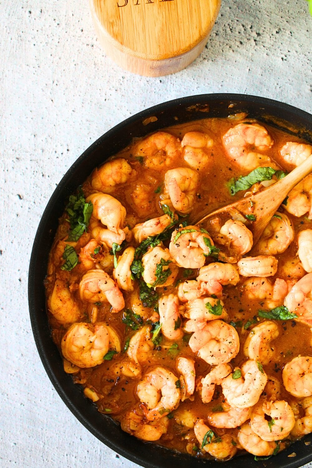 top view of high protein spicy buttered shrimp with a wooden spoon