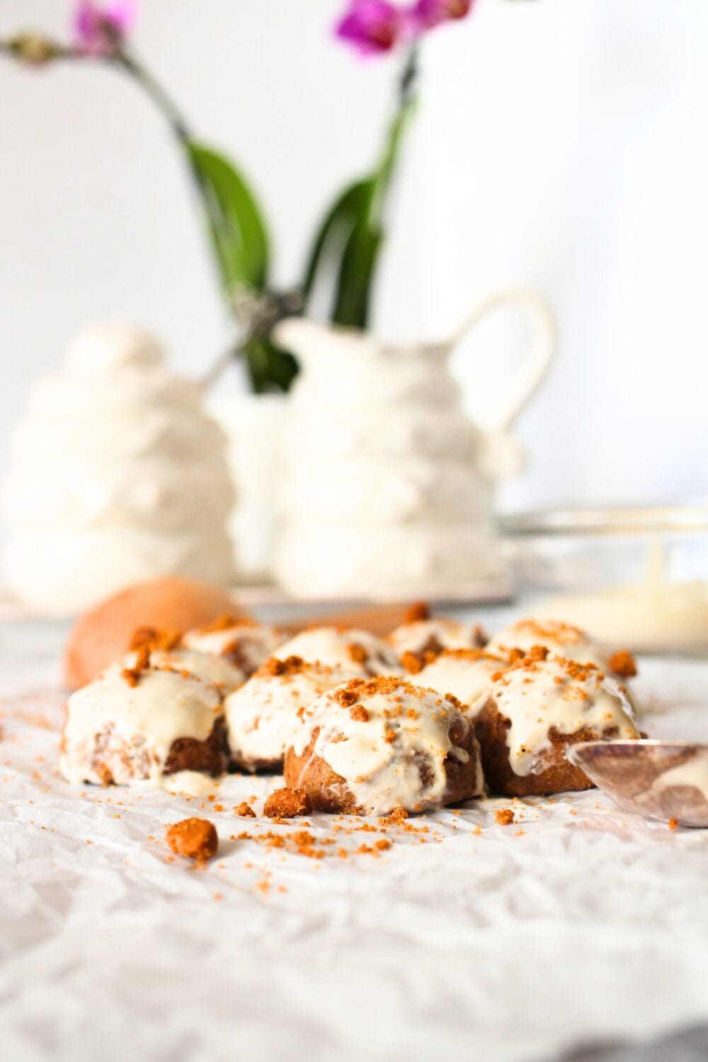 front view of keto speculoos fat bomb truffles with a cream cheese glaze and a tea set in the background