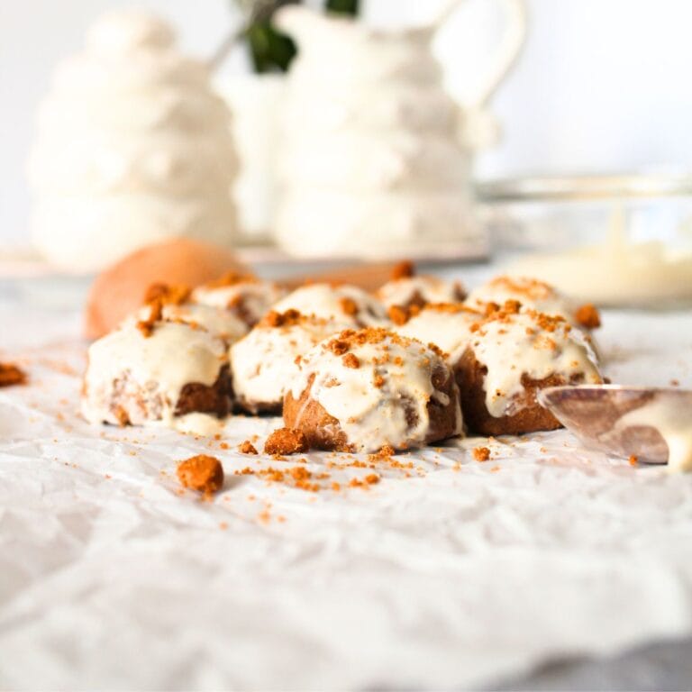front view of keto speculoos fat bomb truffles with a cream cheese glaze and a tea set in the background