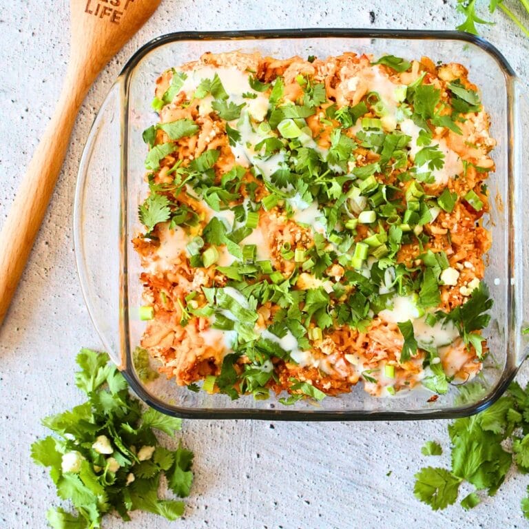 top view of a healthy chicken casserole wtih hot sauce and cilantro on top and a wooden spoon on the side