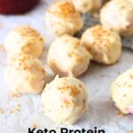 front view of keto high protein white chocolate coconut bites with gold glitter and sugar-free white chocolate in the background