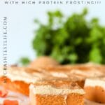 front view of protein carrot cake bar with vanilla protein frosting and greenery in the background