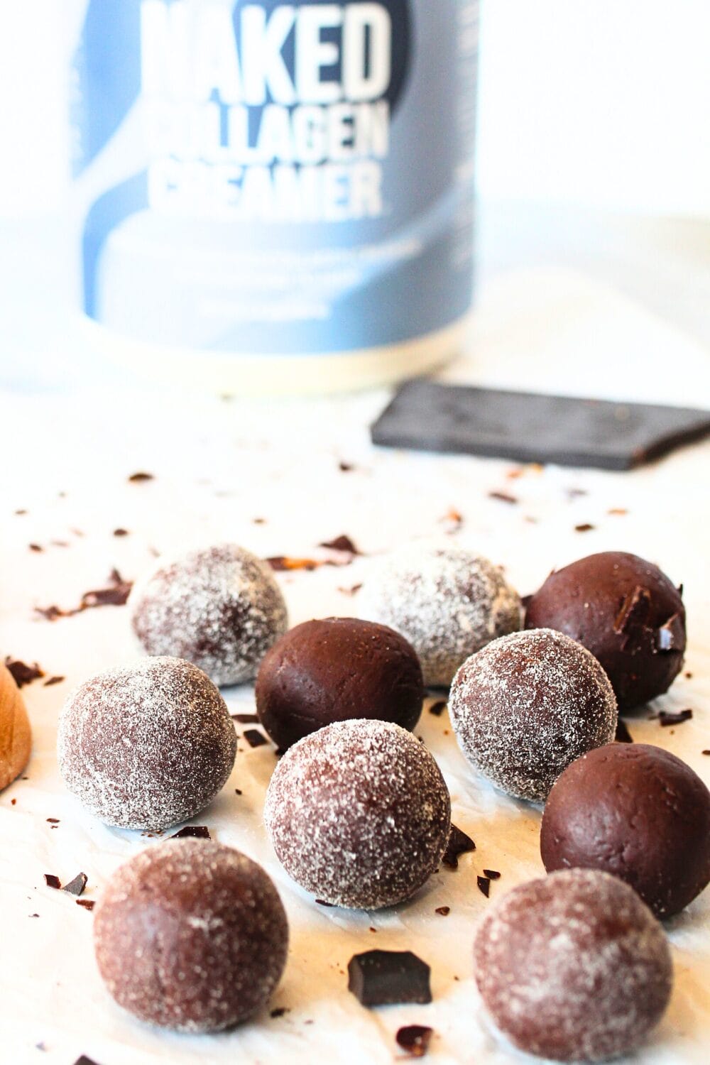 front view of keto collagen chocolate bites with collagen powder and keto chocolate scattered about