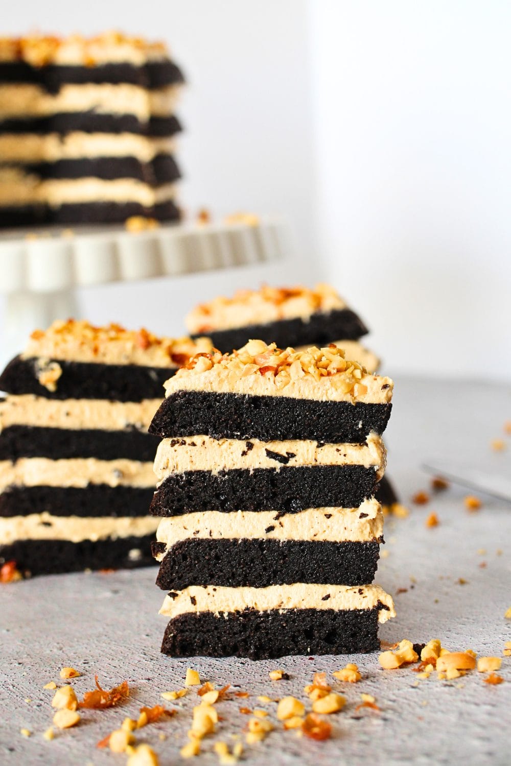 front view of a slice of Keto Reese's Cake with chopped nuts scattered around