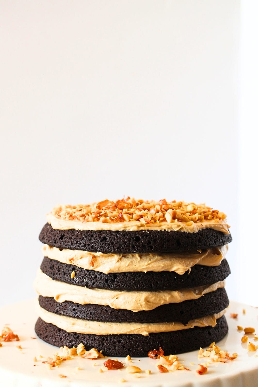 front view of a keto chocolate cake with peanut butter frosting and chopped peanuts on top on a serving platter