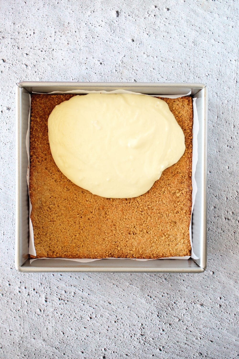 top view of keto cheesecake being poured over keto graham cracker base